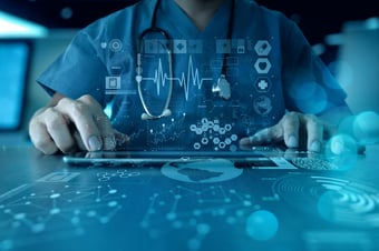  Healthcare professional in blue scrubs using a tablet with transparent digital medical data overlays and blue-teal bokeh lights in the background. 
