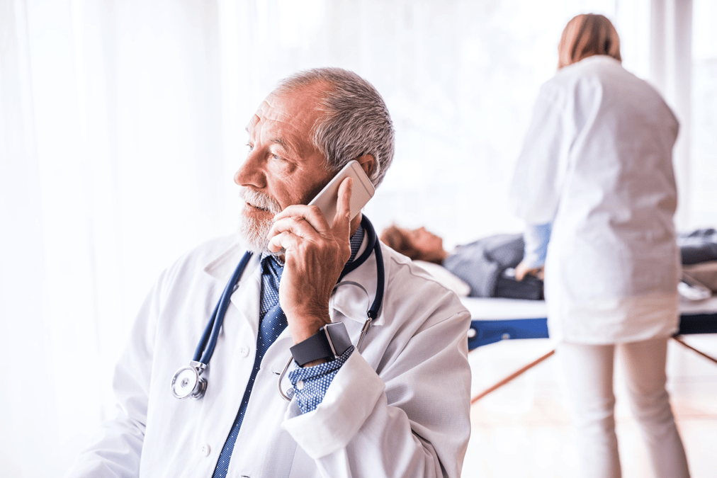 senior-doctor-with-smartphone-in-his-office-P3A8S6Z 